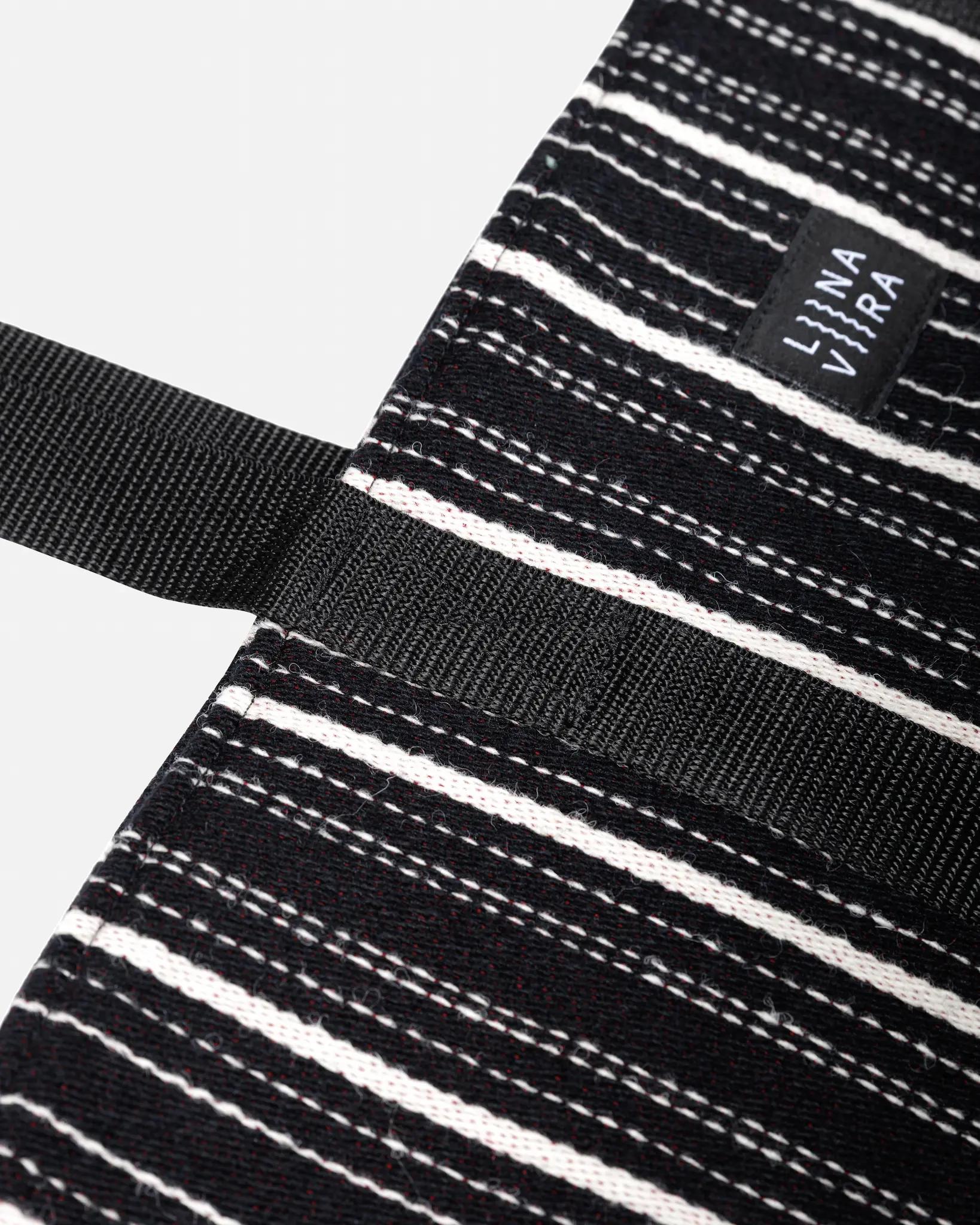 Black and white striped apron with a brand label on a white background